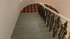 Eine Treppe mit aufwendig gestalteten, schwarzen Balustraden, einer Chandelier und Statuen an den Wänden.
