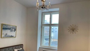 Ein Schlafzimmer mit einem Bett, einem Heizkörper, einem Fenster mit Blick, einer Chandelier und einer Wanduhr.