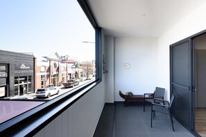 A balcony with a view of a street, a bench, and a door.