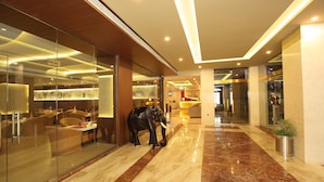 A modern hotel lobby with a marble floor, glass walls, and a statue of an elephant. - The Garuda Hotels (Thrissur)
