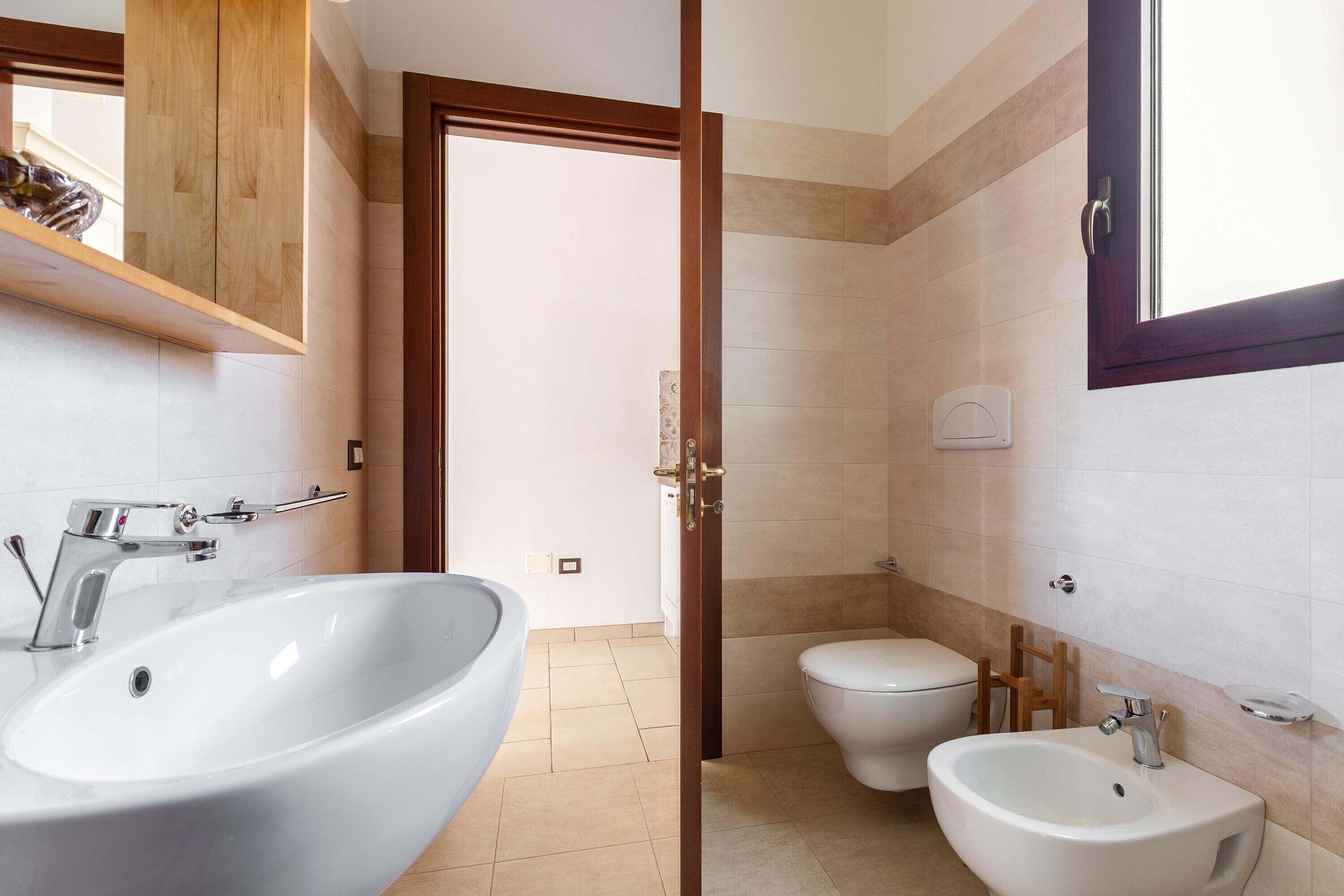 Un baño con un lavamanos grande blanco, un bidé y un inodoro.