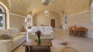 A spacious living area with a white sofa, a wooden coffee table, and a dining table with chairs. - 2283 Villa La Paiara by Perle di Puglia (Melendugno)