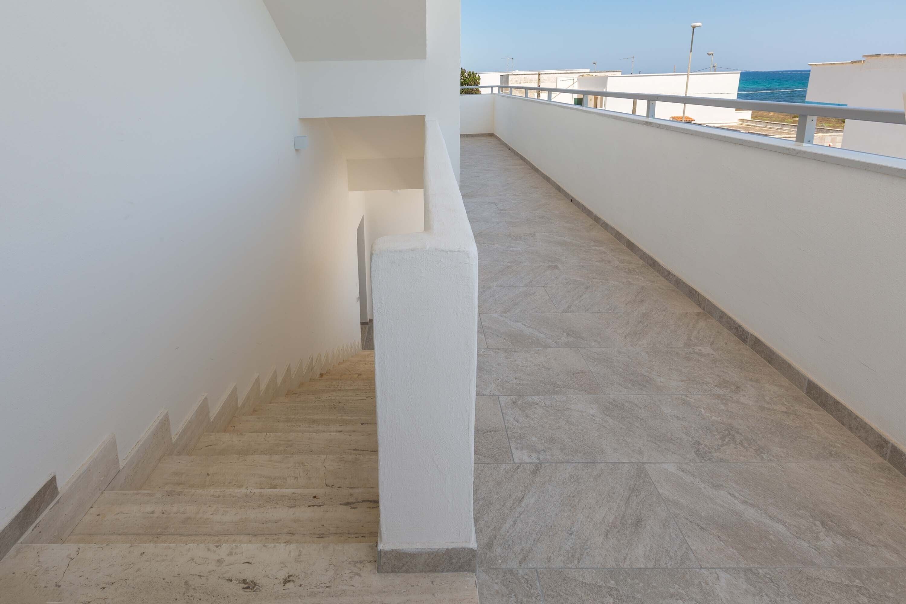 A staircase leading to a balcony with a view of the sea.