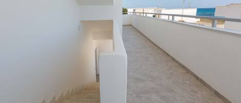 A staircase leading to a balcony with a view of the sea.