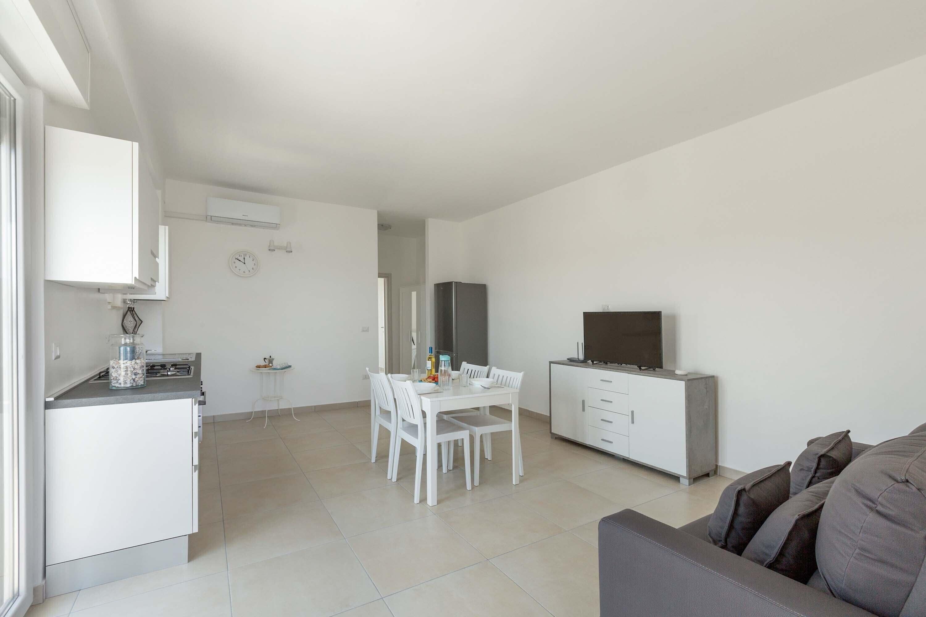 Un espacio habitable moderno y minimalista con comedor, kitchenette y televisor.