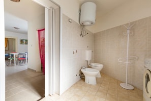 A bathroom with a toilet, bidet, and washing machine.