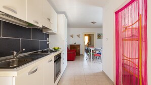 A kitchen with a sink, stove, and cabinets, leading to a dining area with a table and chairs. - 1852 Villa Nataly - Primo Piano by Barbarhouse (Lecce)