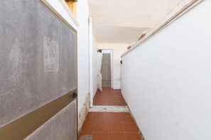 A narrow hallway with a tiled floor, white walls, and a door on the left.