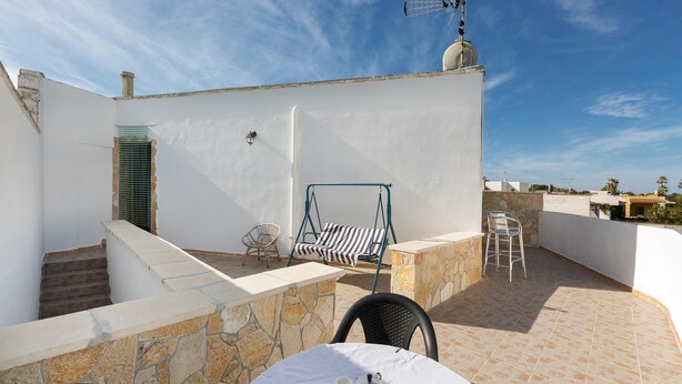 A rooftop terrace with a table set for two, a swing chair, and a stone wall. - 1852 Villa Nataly - Primo Piano by Barbarhouse (Lecce)