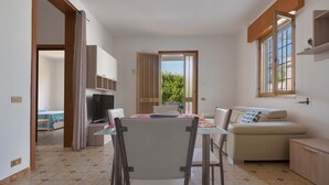 A compact living space with a dining area, a sofa, and a kitchenette. - 2293 Villetta Mare Bello by Barbarhouse (Lecce)