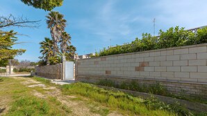 A pathway leading to a building with a brick wall and greenery. - 2293 Villetta Mare Bello by Barbarhouse (Lecce)