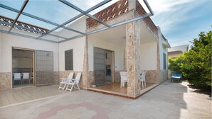 A covered patio area with hexagonal tile flooring, white chairs, and a glass enclosure. - 2293 Villetta Mare Bello by Barbarhouse (Lecce)
