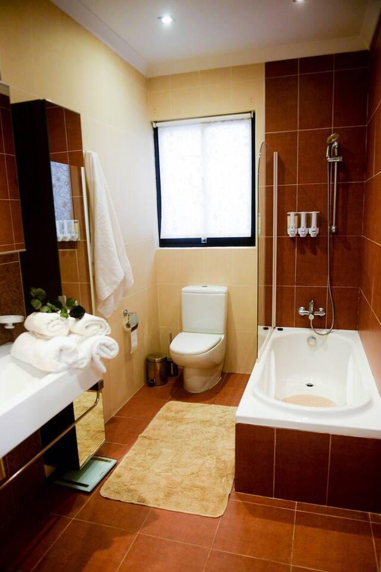 Un baño moderno con inodoro blanco, bañera y zona de ducha.