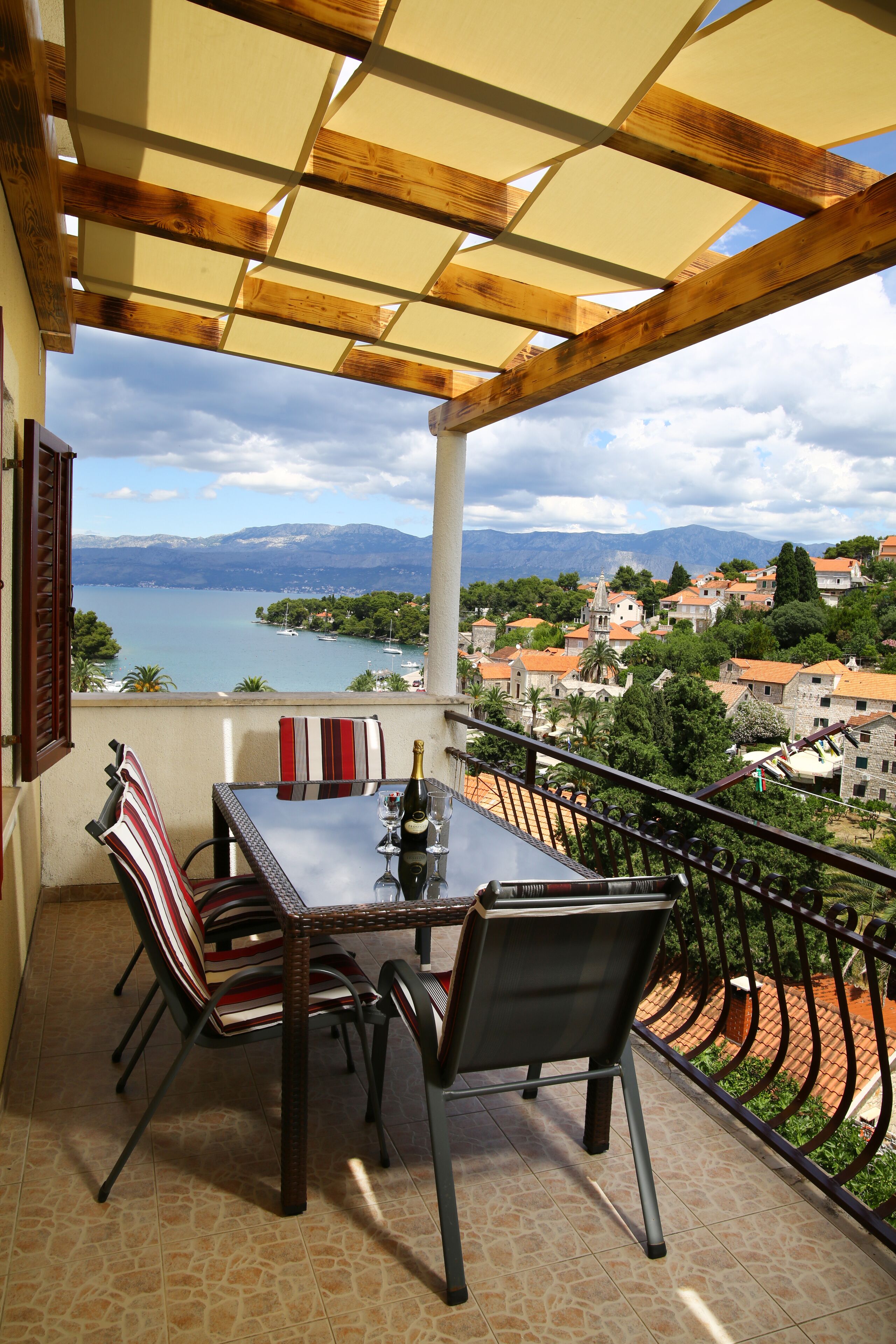 A balcony with a table and chairs, overlooking a lake and a town.