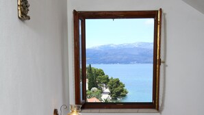 Ein Schlafzimmer mit einem Bett, einem Nachttisch mit Lampe und einem Fenster mit Blick auf einen See und Berge.