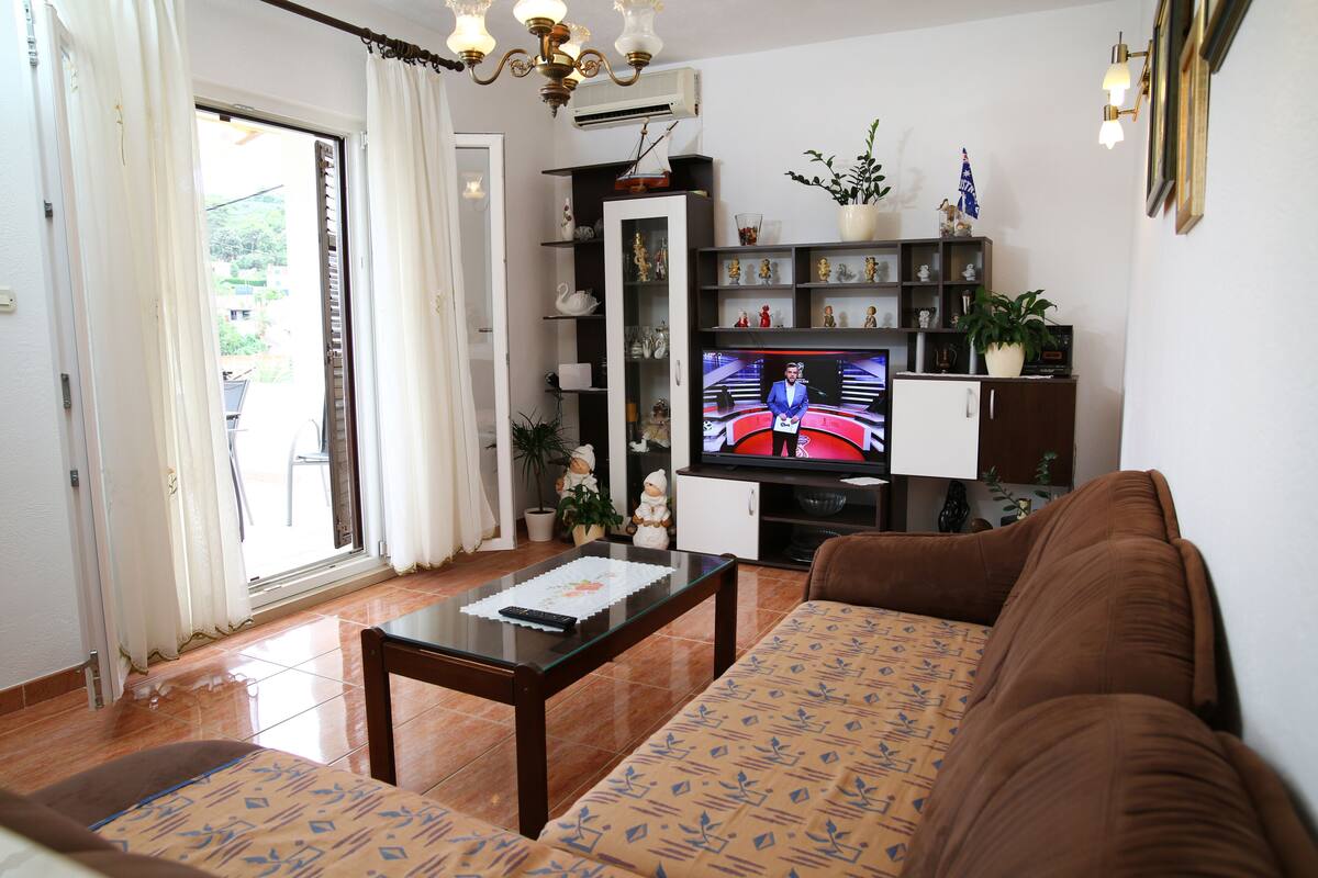 Un salon comprenant un canapé, une table basse, un téléviseur et une bibliothèque.