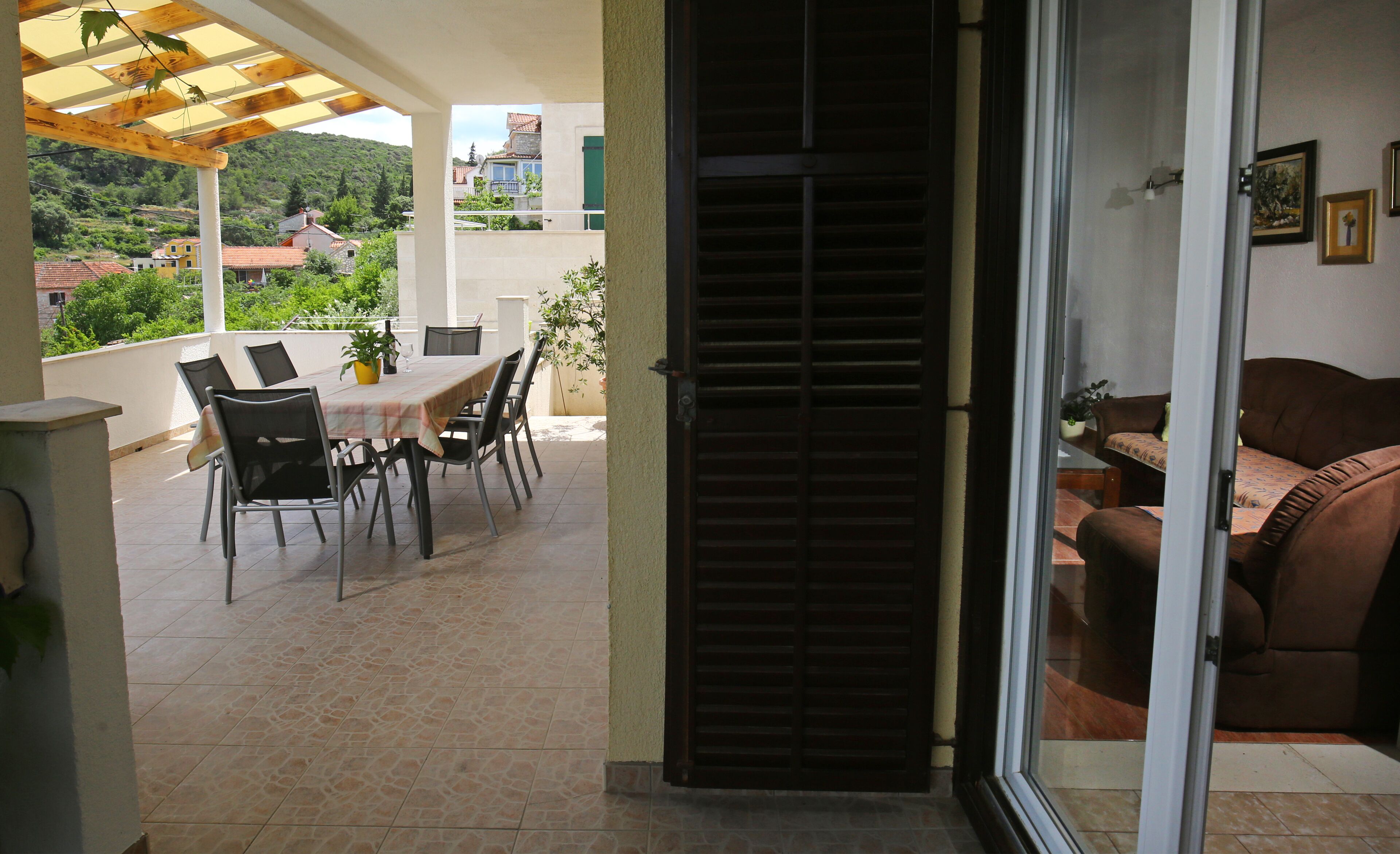 A patio with a table and chairs, a sliding door, and a view of the surrounding area.
