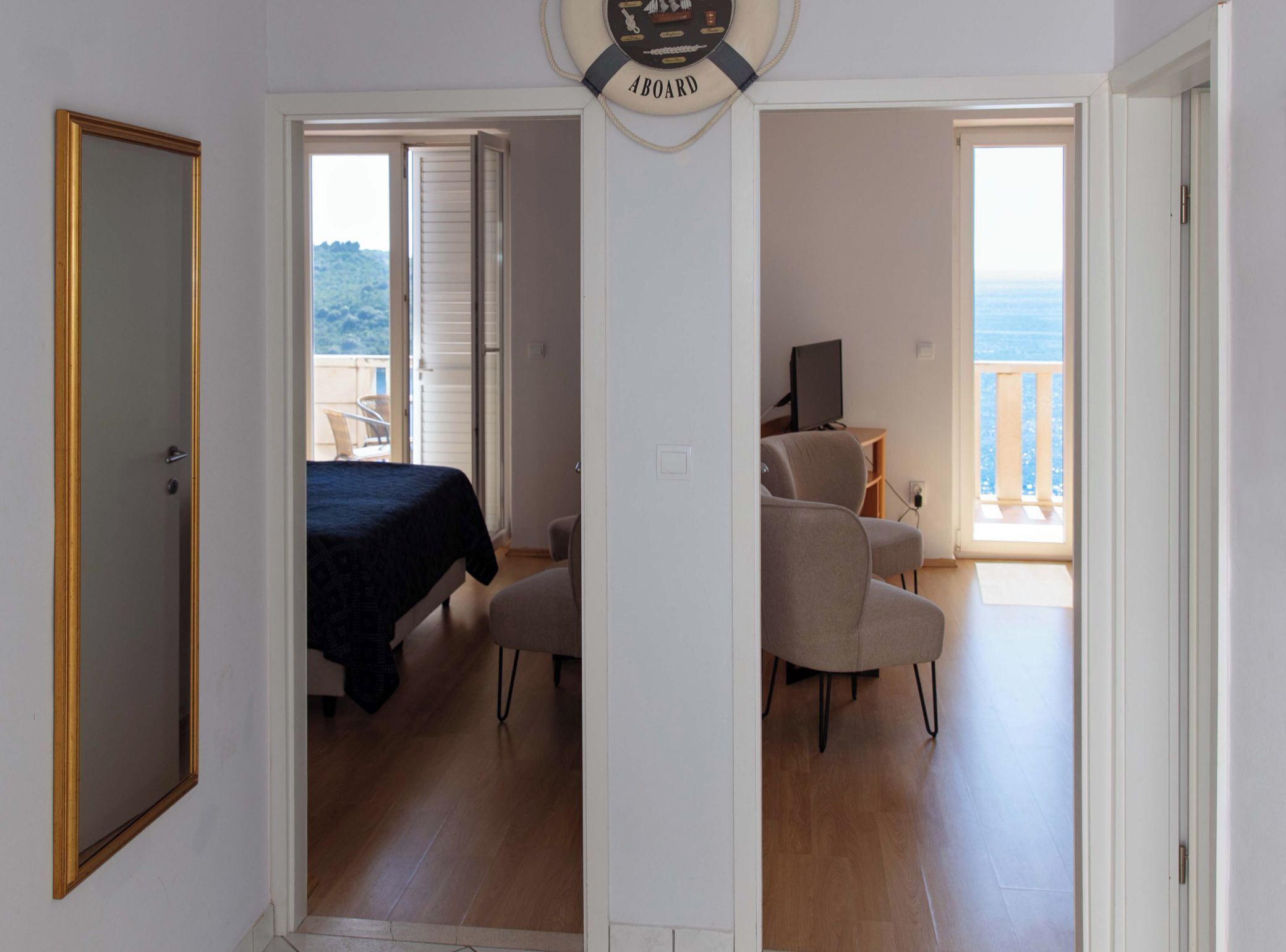 Una habitación con cama, una silla, un escritorio con computadora y un balcón con vistas.
