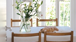 Een eettafel met een bloemenvaas, een brood en houten stoelen.