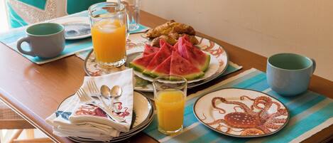 A breakfast table with plates of food, glasses of orange juice, and a striped placemat.