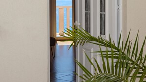 Een gang met betegelde vloer die leidt naar een balkon met uitzicht op zee.
