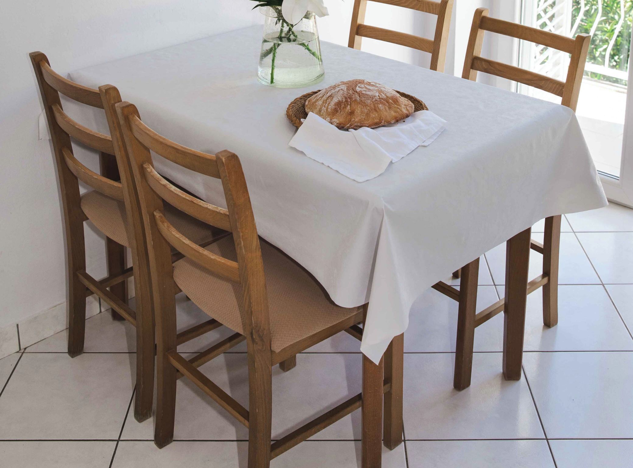 Una mesa de comedor con mantel blanco, rodeada de sillas de madera.