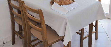 Una mesa de comedor con mantel blanco, rodeada de sillas de madera.