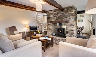 A cozy living room with a stone fireplace, comfortable seating, and a television.