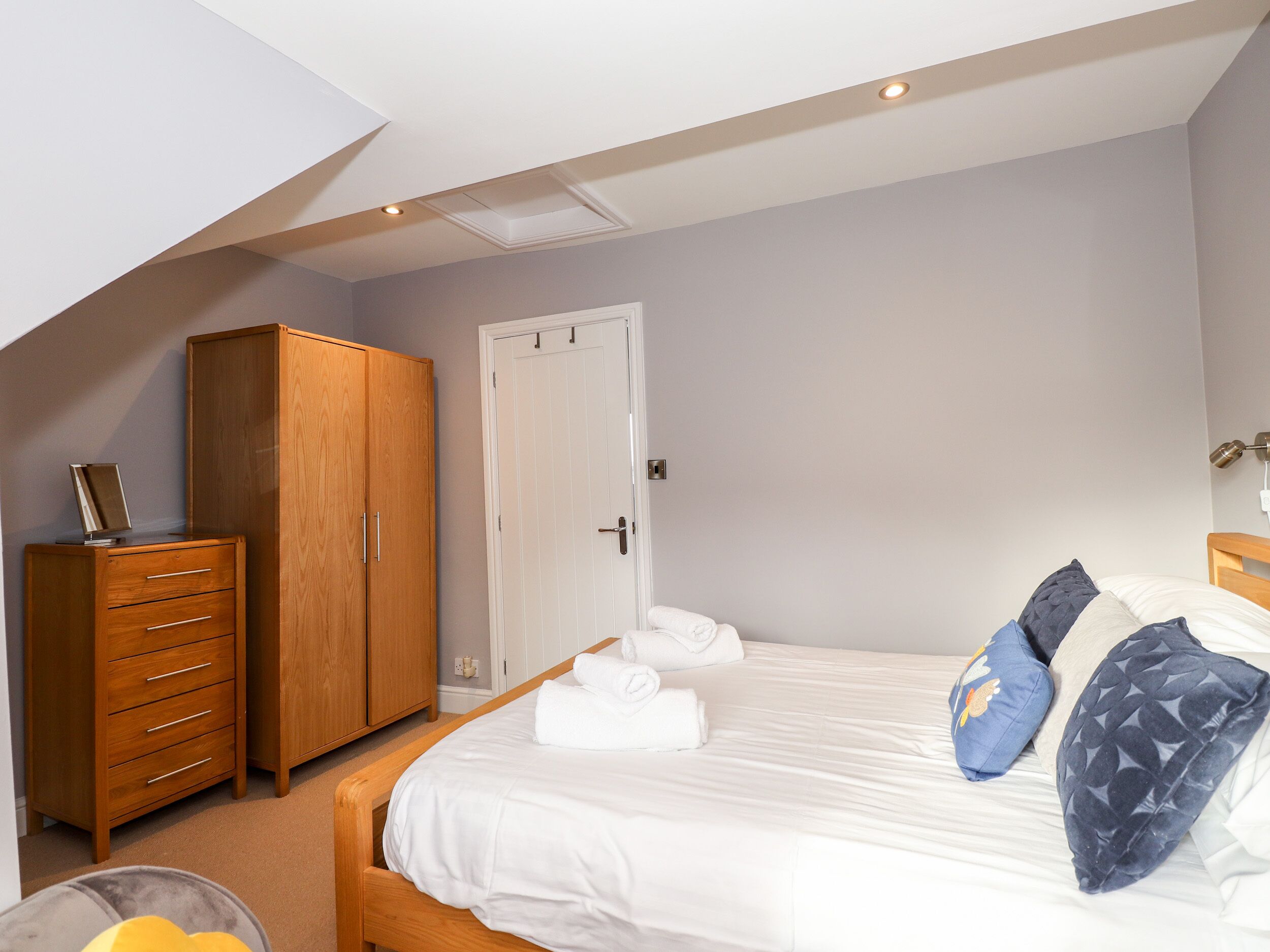 A bedroom with a bed, wooden wardrobe, and a door.