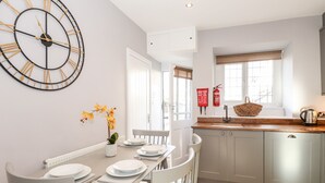 Une cuisine moderne avec des armoires grises, un plan de travail en bois et une grande horloge murale.