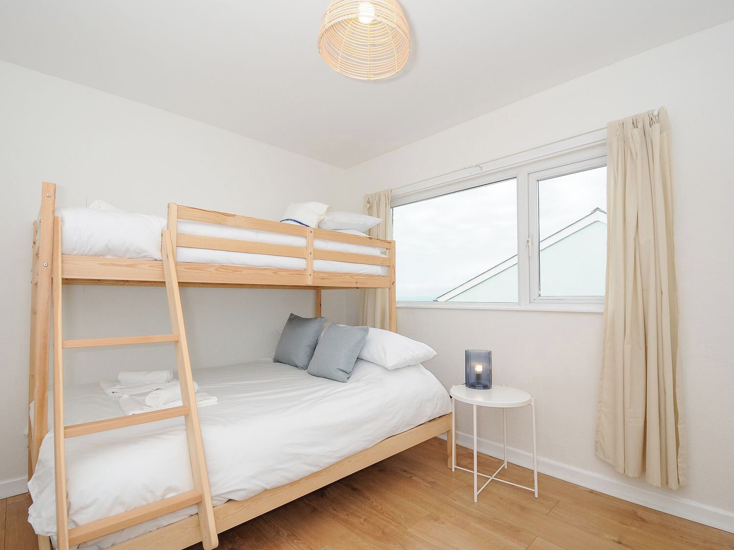 Habitación con literas, una mesita de noche con lámpara y una ventana con cortinas.