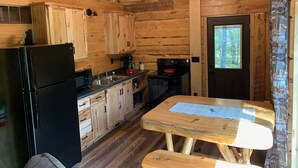A wooden cabin kitchen with a refrigerator, stove, and wooden cabinets.