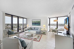 Un salon moderne avec une grande fenêtre, un canapé, une table basse et un téléviseur.