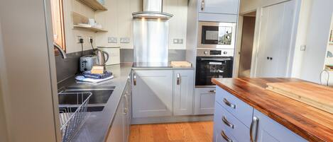 A modern kitchen with stainless steel appliances, wooden countertops, and light-colored cabinetry.