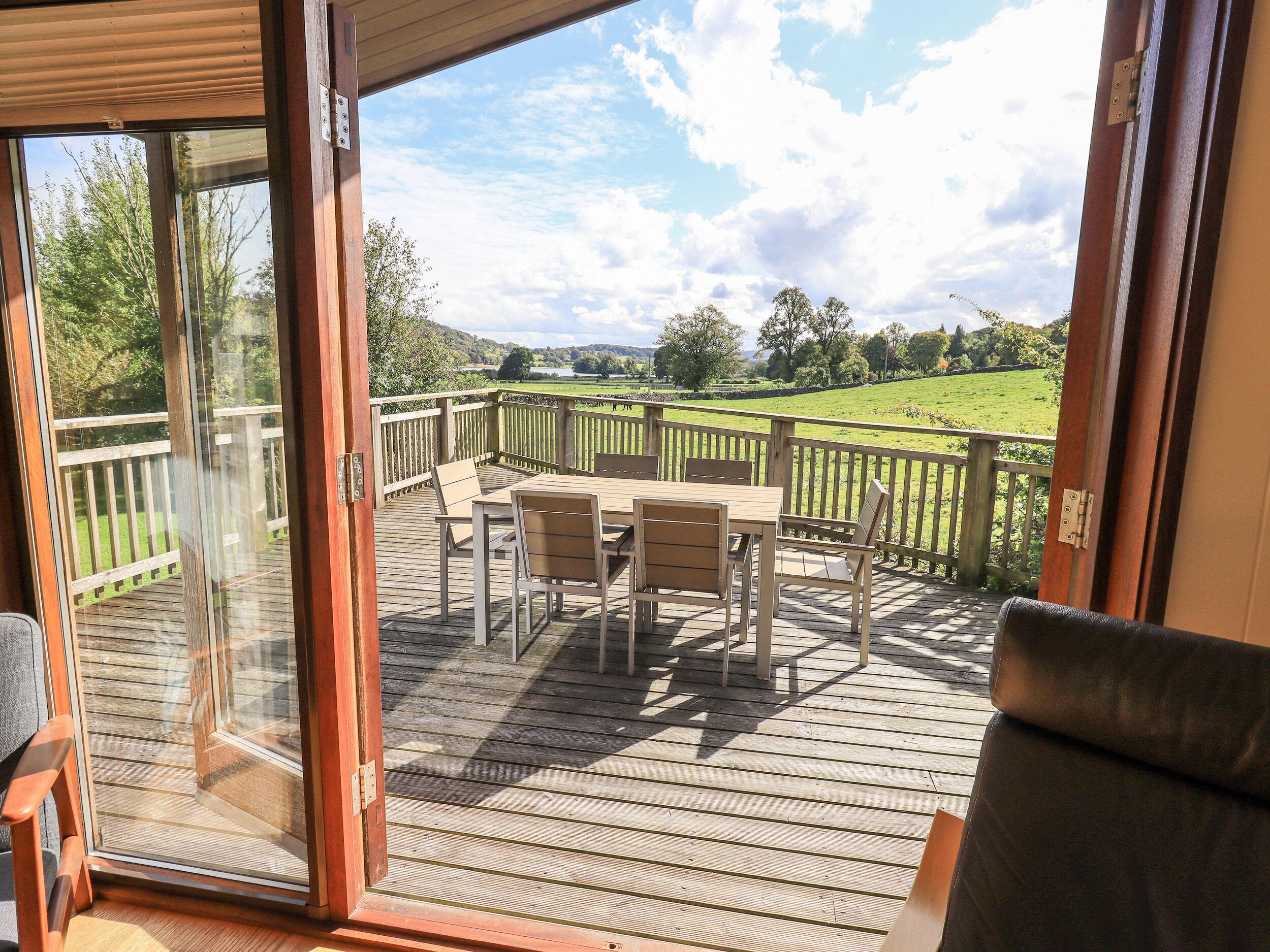 A deck with a table and chairs, overlooking a green landscape.
