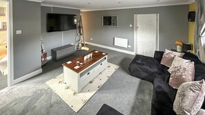 Una sala de estar con sofá, una mesa de centro, un televisor y una escalera con objetos.