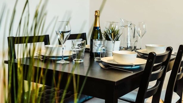 Un tavolo imbandito con piatti, bicchieri e una bottiglia di champagne.