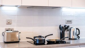 Une cuisine équipée d’un grille-pain, d’une bouilloire, d’une poêle et d’une casserole sur une plaque de cuisson à induction.