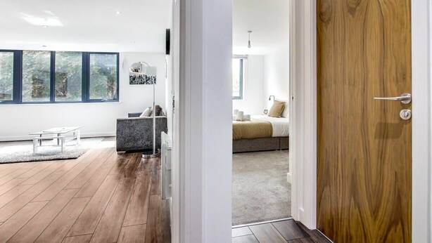 A modern living room with a large window, a sofa, a coffee table, and a rug. - Luxe Getaway - Business | Netflix | WiFi (West Midlands)