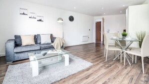 A modern living room with a sofa, coffee table, and dining area. - Luxe Getaway - Business | Netflix | WiFi (West Midlands)