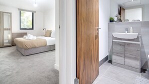 A modern bedroom with a bed, bedside table, and a large window. - Luxe Getaway - Business | Netflix | WiFi (West Midlands)