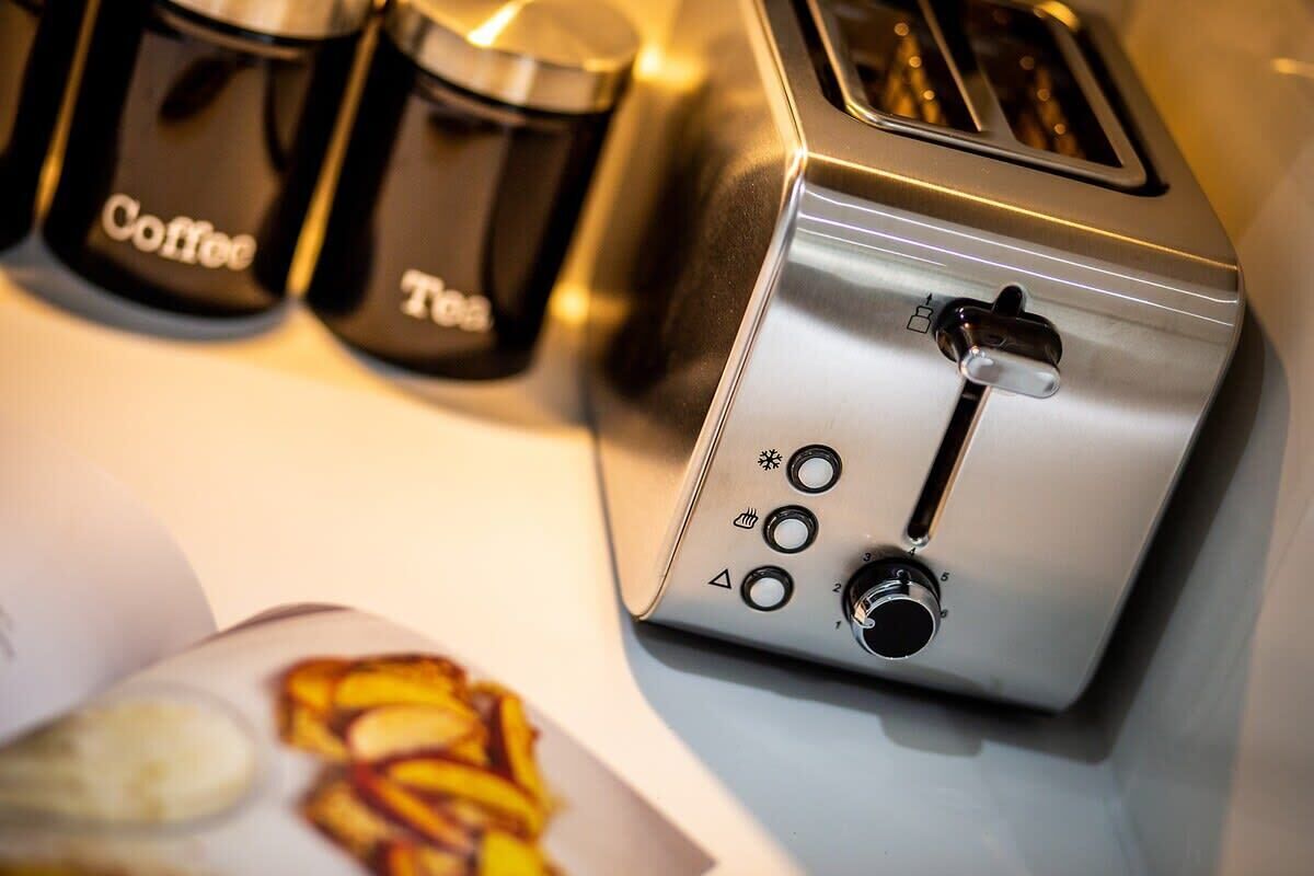Une cuisine équipée d’un grille-pain, de deux récipients étiquetés « Café » et « Thé », et d’une assiette contenant de la nourriture.
