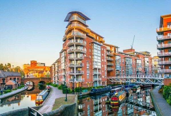 A modern building with multiple balconies and a canal with boats.