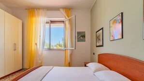 A bedroom with a bed, a wardrobe, a window with curtains, and artwork on the wall. - 2864 Villa Carminella by Barbarhouse (Lecce)