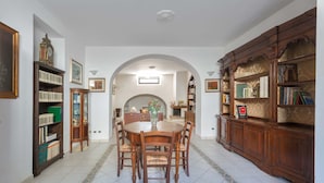 Un coin repas avec une table ronde et des chaises, bordé de bibliothèques en bois et d’un meuble décoratif.