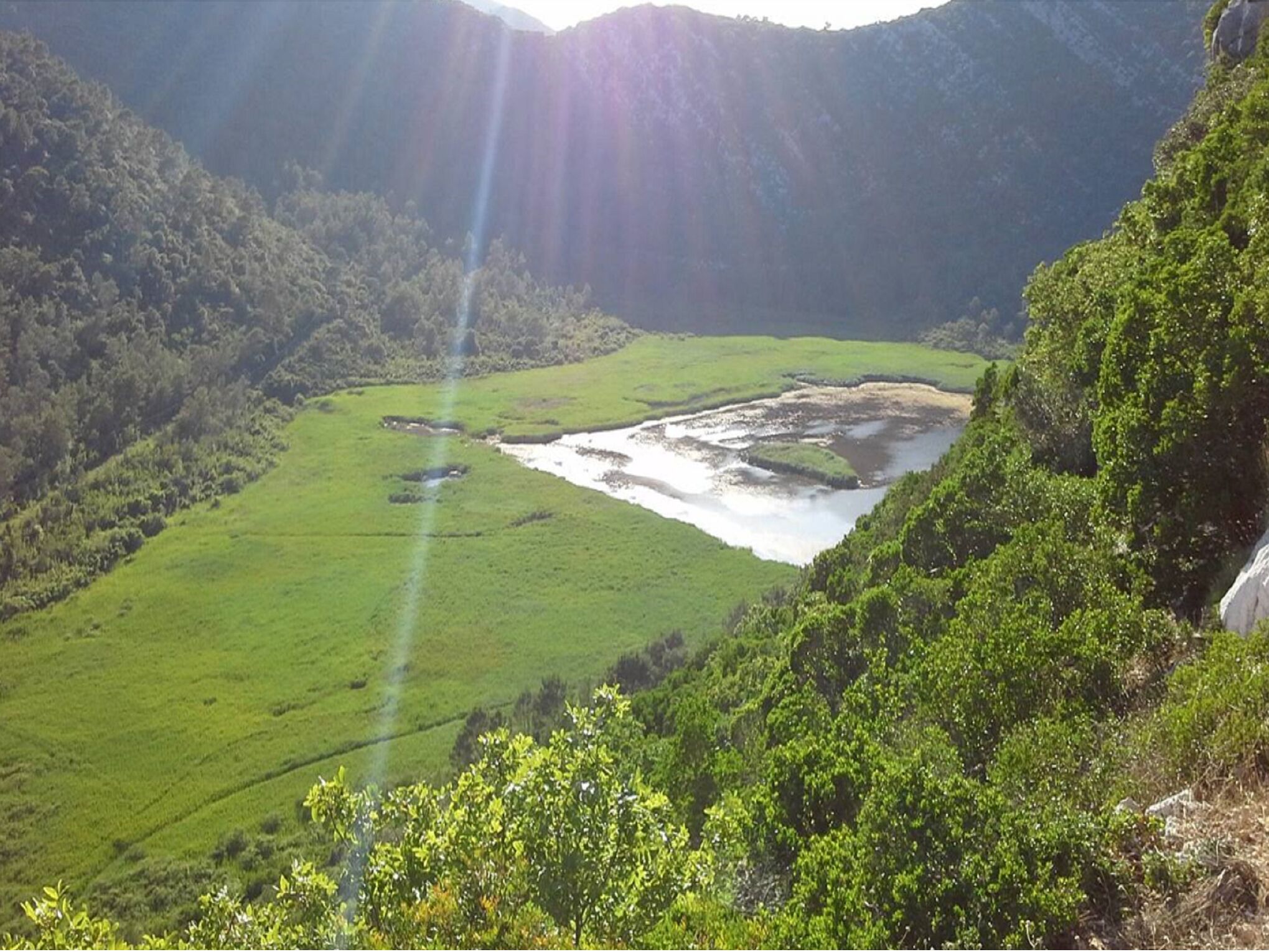 Une vallée traversée par une rivière, entourée de collines boisées.