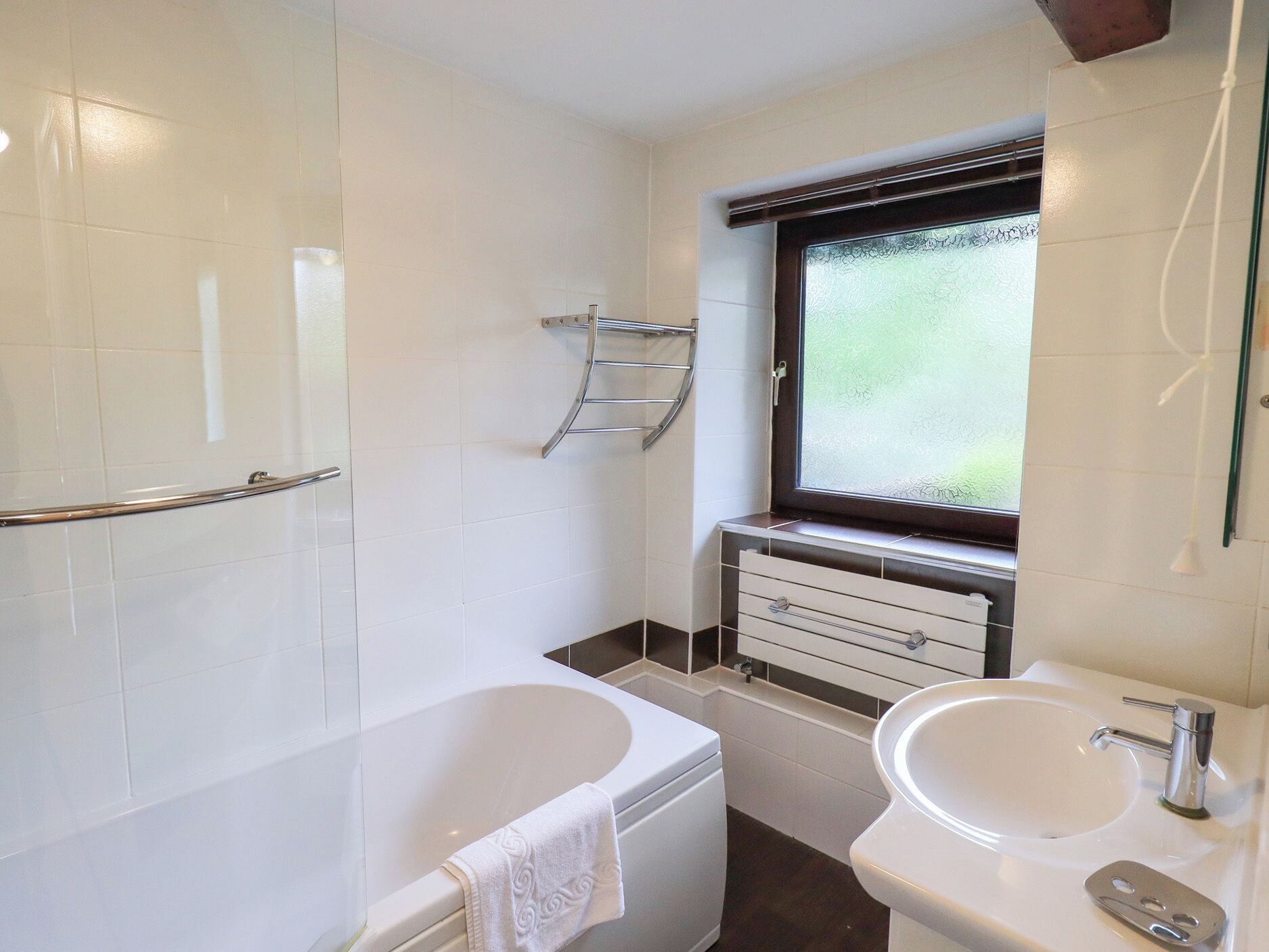 A modern bathroom with a bathtub, a sink, and a window.