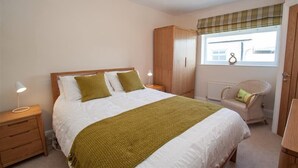 A bedroom with a bed, nightstands, a wardrobe, a window with a view, and a chair. - Gable End (Keswick)
