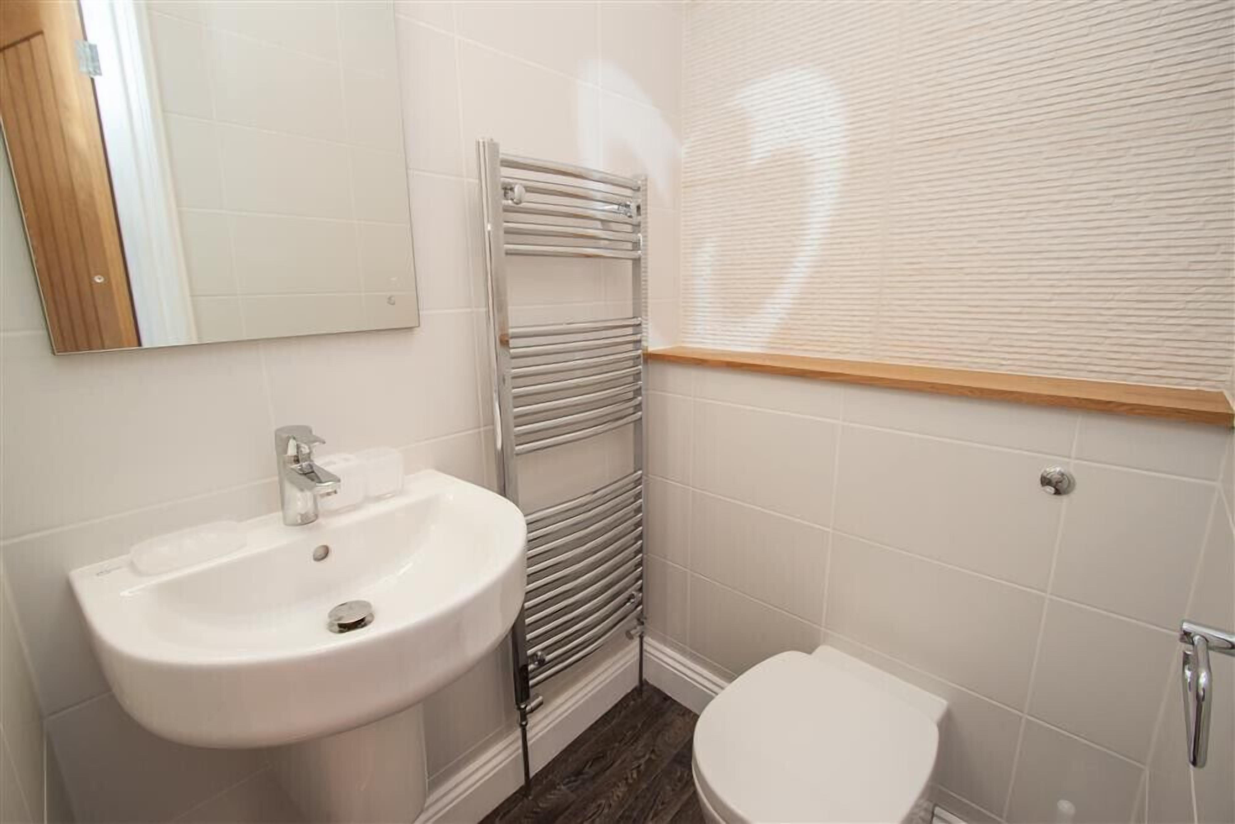A bathroom with a white sink, a toilet, and a towel rack.