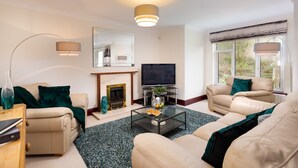 A living room with a fireplace, a television, and two sofas. - Beech View (Ambleside)